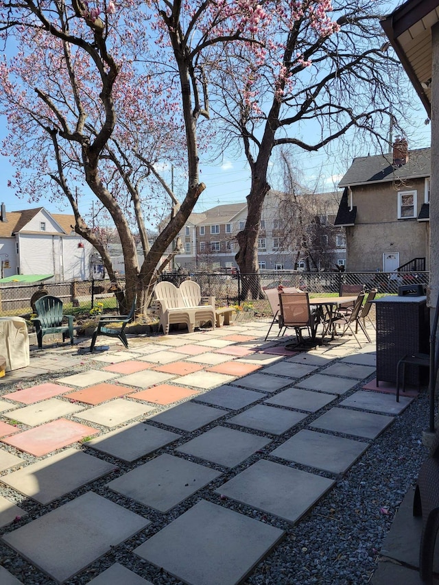 view of patio / terrace with central air condition unit, fence, and a residential view