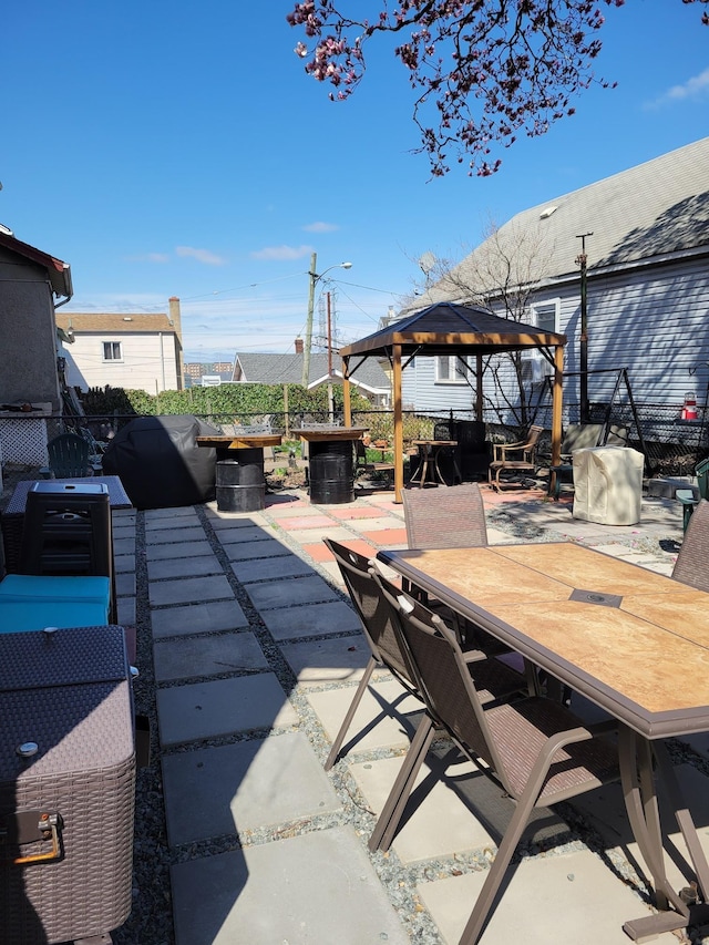 view of patio with fence, outdoor dining space, and a gazebo
