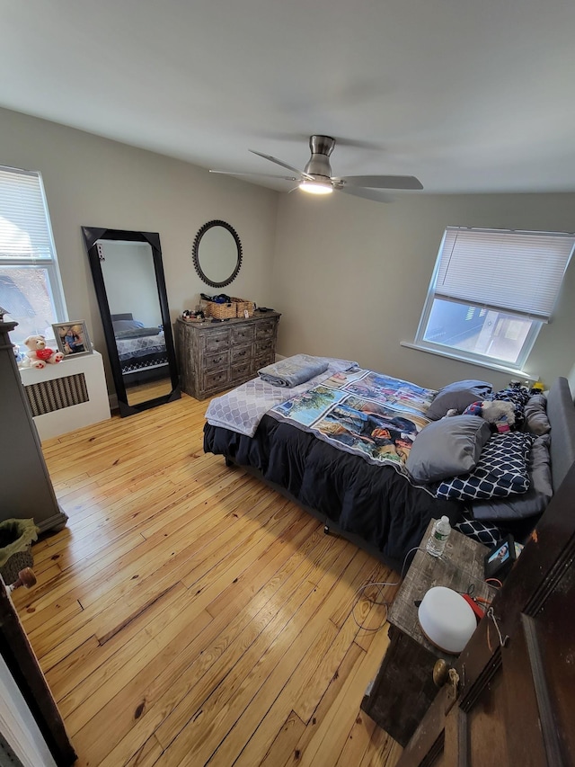 bedroom with multiple windows, wood-type flooring, and a ceiling fan