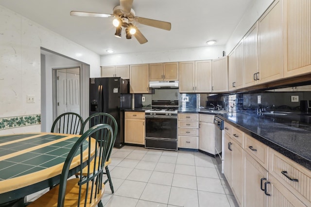 kitchen featuring ceiling fan, stainless steel dishwasher, black fridge, under cabinet range hood, and gas range oven
