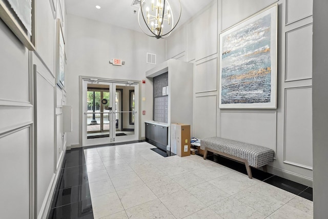 foyer entrance featuring french doors, an inviting chandelier, and a high ceiling