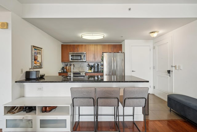 kitchen featuring sink, appliances with stainless steel finishes, tasteful backsplash, kitchen peninsula, and a breakfast bar area