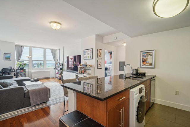 kitchen featuring sink, stainless steel dishwasher, kitchen peninsula, washer / clothes dryer, and a kitchen bar