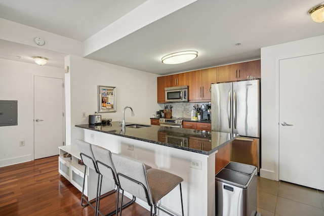 kitchen featuring kitchen peninsula, a breakfast bar, stainless steel appliances, sink, and electric panel