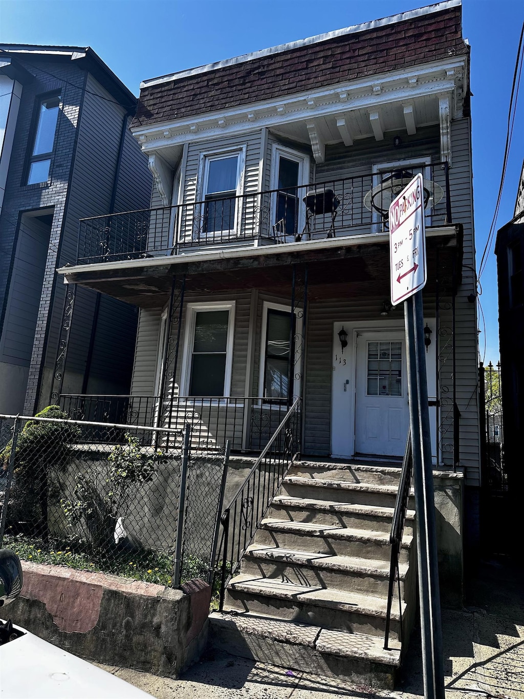 townhome / multi-family property featuring roof with shingles, mansard roof, a balcony, and covered porch