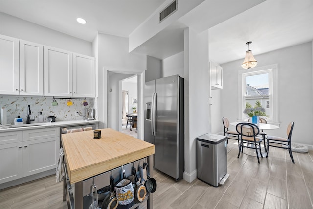 33 Duer Pl, Weehawken, NJ 07086 - kitchen featuring stainless steel fridge, light countertops, white cabinetry, tasteful backsplash, and recessed lighting