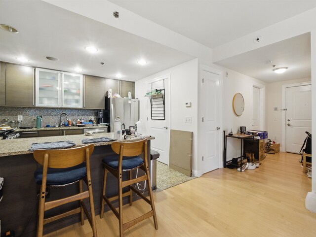 10 Regent St Unit 308, Jersey City, NJ 07302 - kitchen with a sink, light wood-type flooring, decorative backsplash, glass insert cabinets, and light stone countertops