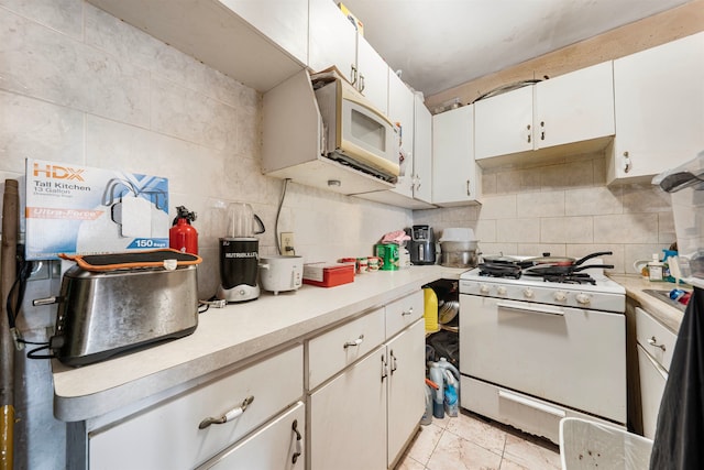 kitchen featuring backsplash, white appliances, light tile patterned flooring, and white cabinets