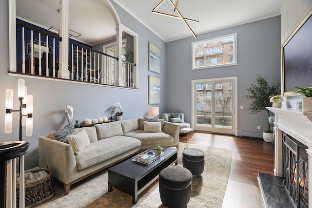 living room with a baseboard heating unit, hardwood / wood-style floors, crown molding, and a premium fireplace