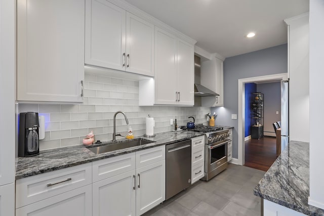 kitchen with white cabinetry, sink, appliances with stainless steel finishes, wall chimney exhaust hood, and backsplash