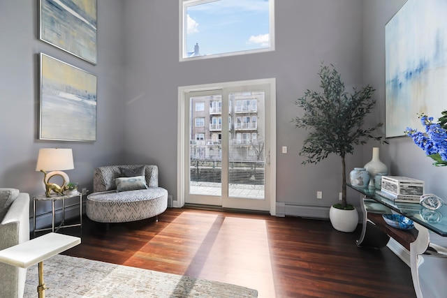 doorway with dark wood-type flooring, a high ceiling, and a baseboard heating unit