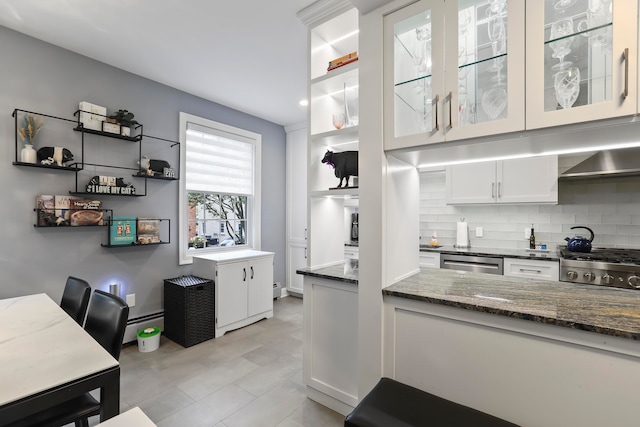 kitchen featuring appliances with stainless steel finishes, dark stone countertops, white cabinets, a baseboard radiator, and decorative backsplash