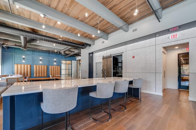 kitchen with light stone counters, a breakfast bar, and beamed ceiling