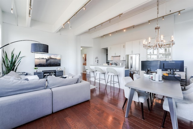 living room with rail lighting, dark wood-type flooring, and a chandelier