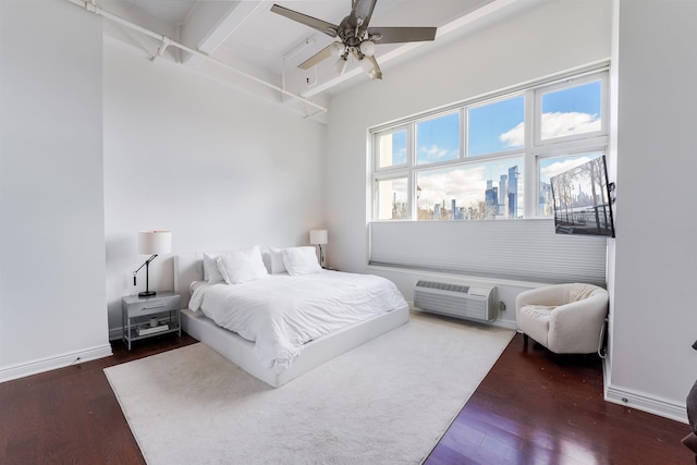 bedroom featuring beamed ceiling, dark hardwood / wood-style flooring, ceiling fan, and a wall unit AC