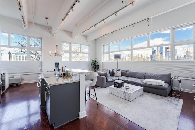 living room featuring dark hardwood / wood-style flooring, a notable chandelier, beam ceiling, and track lighting