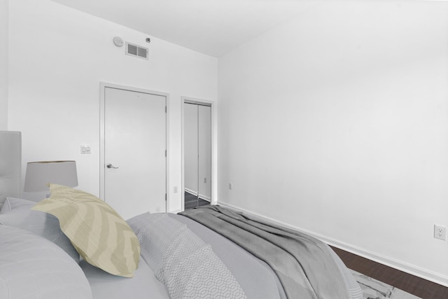 bedroom featuring baseboards, visible vents, dark wood-style floors, and a closet