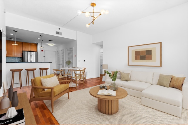 living room featuring visible vents, wood finished floors, and a chandelier