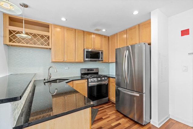 kitchen with light brown cabinetry, appliances with stainless steel finishes, a sink, light wood-style floors, and backsplash