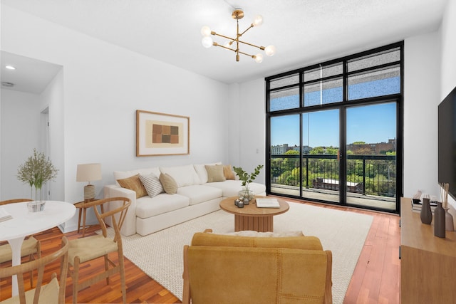 living room with a notable chandelier, a wall of windows, and wood finished floors