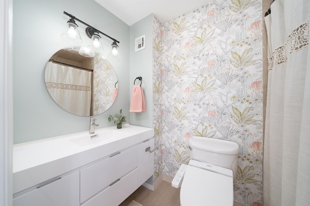 bathroom with visible vents, vanity, toilet, and wallpapered walls