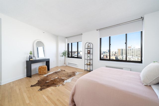 bedroom with a view of city, multiple windows, and wood finished floors