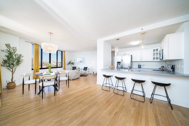 kitchen with light wood-style flooring, stainless steel appliances, a breakfast bar, decorative backsplash, and glass insert cabinets