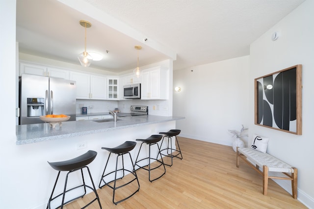 kitchen with glass insert cabinets, a peninsula, appliances with stainless steel finishes, and a breakfast bar area