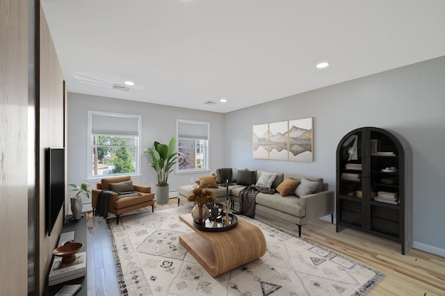 living room with arched walkways, recessed lighting, visible vents, light wood-style floors, and baseboards