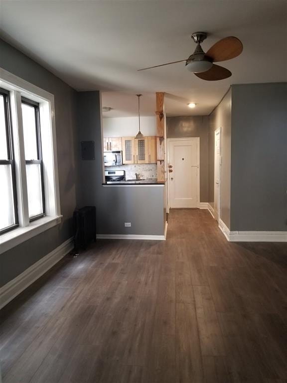 unfurnished living room featuring dark wood-type flooring and ceiling fan