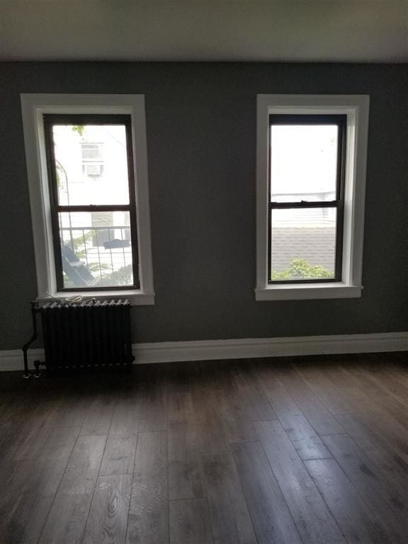 unfurnished room with dark wood-type flooring and radiator heating unit