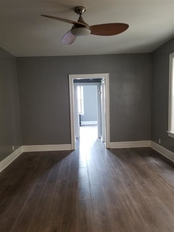 empty room with dark wood-type flooring and ceiling fan