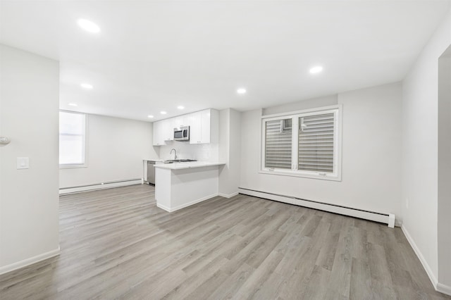 418 7th St, Union City, NJ 07087 - kitchen with a baseboard heating unit, stainless steel appliances, baseboard heating, white cabinets, and light wood-style flooring