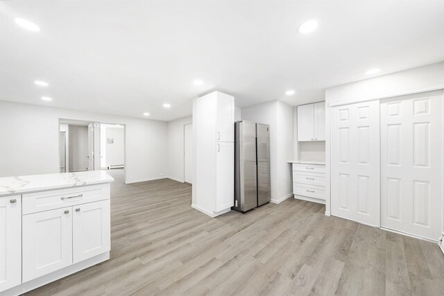 418 7th St, Union City, NJ 07087 - kitchen with freestanding refrigerator, light wood-style flooring, white cabinets, light stone countertops, and recessed lighting