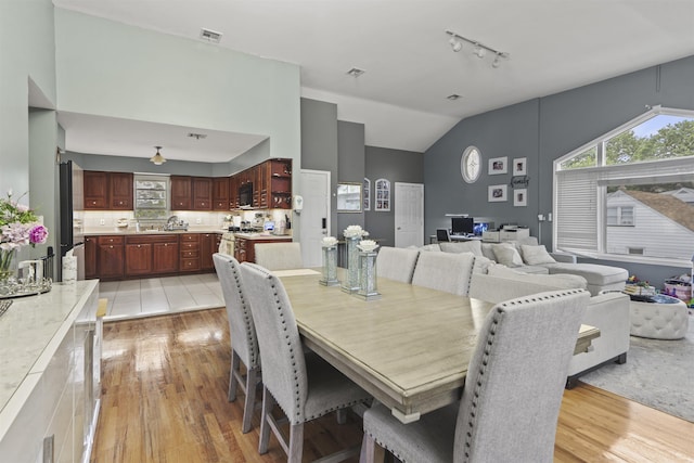 8901 Newkirk Ave, North Bergen, NJ 07047 - dining room featuring light wood finished floors, rail lighting, and high vaulted ceiling