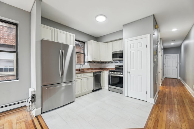 12 Audubon Ave Unit 305, Jersey City, NJ 07305 - kitchen with a sink, stainless steel appliances, white cabinetry, baseboards, and dark countertops