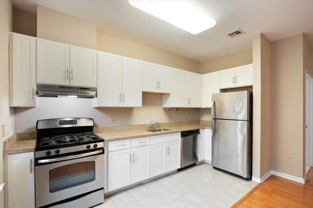 25 Duncan Ave Unit 210, Jersey City, NJ 07304 - kitchen with stainless steel appliances, under cabinet range hood, light countertops, white cabinets, and light wood-type flooring