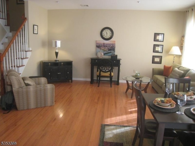 living area featuring stairway, light wood-style flooring, and baseboards
