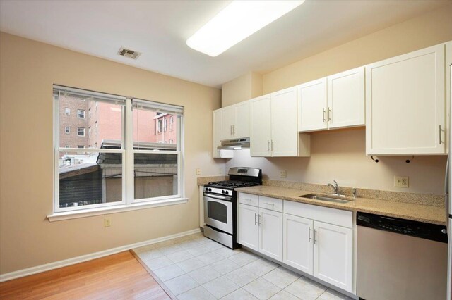 25 Duncan Ave Unit 210, Jersey City, NJ 07304 - kitchen with appliances with stainless steel finishes, under cabinet range hood, white cabinets, light stone counters, and light wood-style flooring