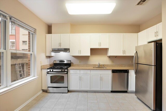 25 Duncan Ave Unit 210, Jersey City, NJ 07304 - kitchen with stainless steel appliances, under cabinet range hood, light countertops, white cabinetry, and light tile patterned floors