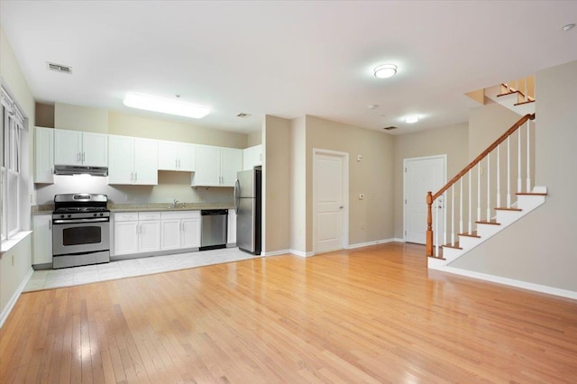25 Duncan Ave Unit 210, Jersey City, NJ 07304 - kitchen with stainless steel appliances, under cabinet range hood, light wood-style flooring, white cabinets, and light countertops