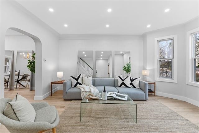 living area featuring arched walkways, light wood-style flooring, baseboards, and recessed lighting