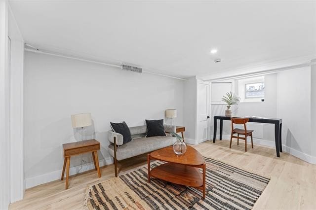 living area featuring baseboards, visible vents, and light wood-style floors