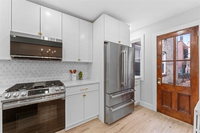 kitchen with white cabinets, decorative backsplash, light wood-style flooring, stainless steel appliances, and light countertops