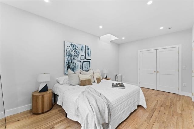 bedroom featuring light wood finished floors, a closet, recessed lighting, and baseboards