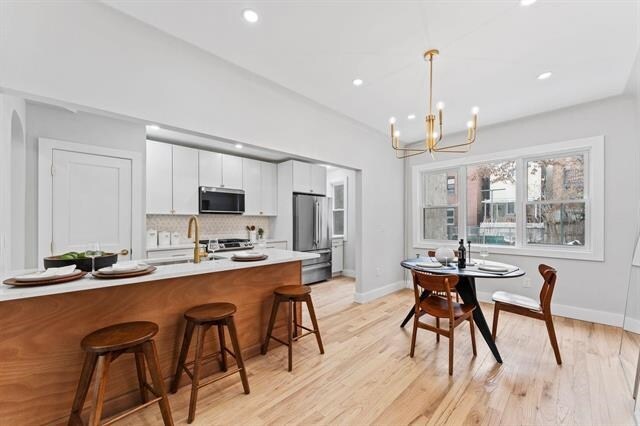 kitchen featuring a breakfast bar, decorative light fixtures, tasteful backsplash, appliances with stainless steel finishes, and a sink