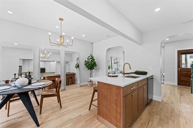 kitchen with a chandelier, a sink, light countertops, stainless steel dishwasher, and brown cabinets