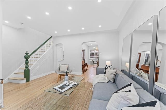 living area featuring stairs, arched walkways, wood finished floors, and recessed lighting