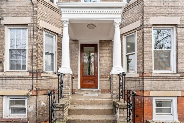 view of exterior entry featuring brick siding