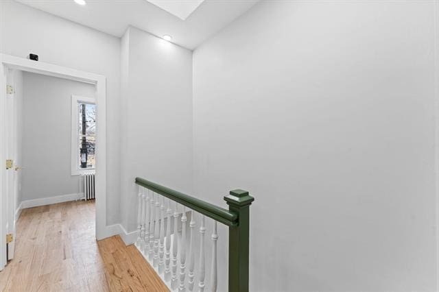 hall featuring recessed lighting, radiator heating unit, light wood-style floors, an upstairs landing, and baseboards